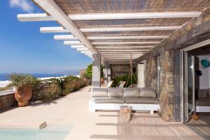 a patio with couches sitting under a pergola at Mykonos Rocks Villas & Suites in Mikonos