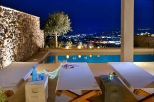 a patio with a table and a pool at night at Mykonos Rocks Villas & Suites in Mikonos