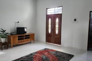 sala de estar con puerta de madera y TV en Astaka Homestay Kok Lanas, en Ketereh