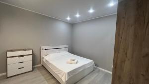 Un pequeño dormitorio con una cama blanca y un tocador en ЖК Ауэзова1 en Kokshetau