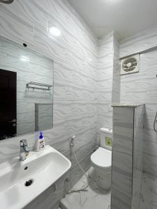 a white bathroom with a sink and a toilet at Karibu house in Dar es Salaam