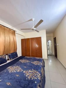 a bedroom with a blue bed and a ceiling fan at Karibu house in Dar es Salaam