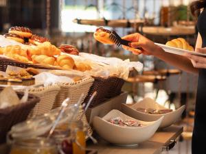 a woman is serving food at a buffet at Mercure Bangkok Sukhumvit 24 in Bangkok