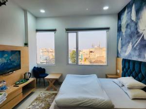 een slaapkamer met een bed, een bureau en 2 ramen bij HolidayVilla-A Residential Boutique Hotel-Newly Renovated in Amritsar