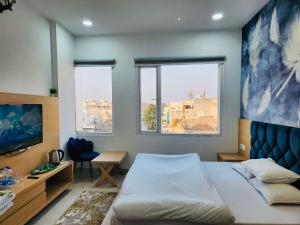 a bedroom with a bed and a desk and two windows at HolidayVilla-A Residential Boutique Hotel-Newly Renovated in Amritsar