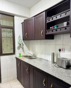 cocina con armarios marrones, fregadero y ventana en Karibu house en Dar es Salaam