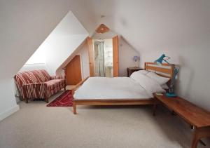 a bedroom with a bed and a chair in a attic at Relaxing townhouse in the heart of Bridport in Bridport