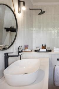 a white bathroom with a sink and a mirror at Simbavati Mvubu Cottage in Timbavati Game Reserve