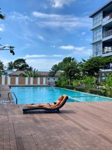una donna sdraiata su un'amaca accanto alla piscina di Chez Wanida - apartment Krabi a Klong Muang Beach