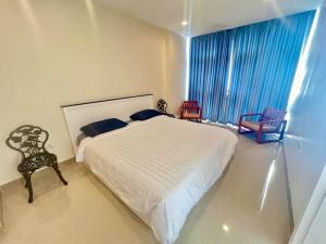 a bedroom with a large white bed and two chairs at Chez Wanida - apartment Krabi in Klong Muang Beach