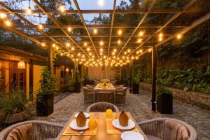 a patio with a table and chairs and lights at The Weir House in Ulapane