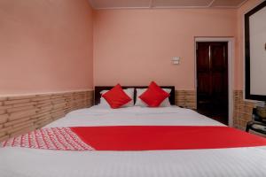 a bedroom with a large bed with red pillows at Collection O Trinayan Associates in Dibrugarh