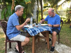 dos hombres sentados en una mesa comiendo comida en Yapahuwa Oasis en Maho