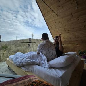 a man and a woman sitting on a bed at Cottage Sataplia in Kutaisi