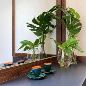 einen Tisch mit zwei Tassen, einem Spiegel und Pflanzen in der Unterkunft Benzen Boutique Stays in Đà Nẵng