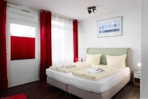 a bedroom with a white bed with red curtains at Zuflucht in Schönberger Strand