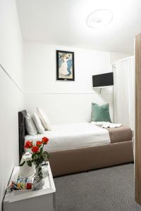 a bedroom with a bed with a vase of flowers on a table at Lancaster Court Hotel in London