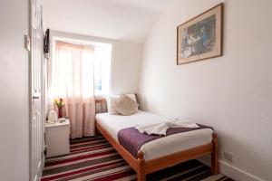 a small bedroom with a bed and a window at Lancaster Court Hotel in London
