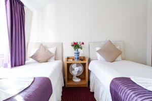 two beds in a room with purple curtains at Lancaster Court Hotel in London
