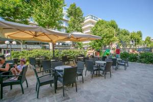 - un restaurant avec des tables, des chaises et un grand parasol dans l'établissement Hotel Atlas, à Rimini