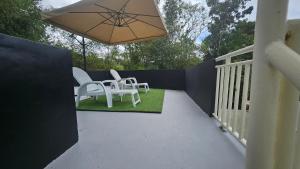 eine Terrasse mit weißen Stühlen und einem Sonnenschirm in der Unterkunft A touch of Pink secret garden in Puerto Princesa