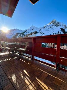 een terras met stoelen en een tafel met bergen op de achtergrond bij ARC 1950 - cozy apartment with mountain view in Arc 1950