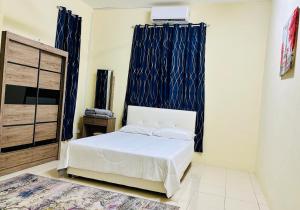 a bedroom with a white bed and blue curtains at Rada Guesthouse in Yan