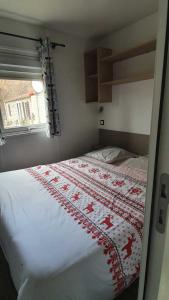 a bedroom with a bed with a red and white blanket at Camping L'Enclave mobil-home in Estavar