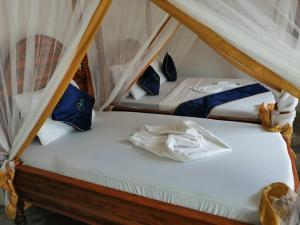 2 camas con sábanas blancas y almohadas azules en Zangreen Bungalows en Jambiani