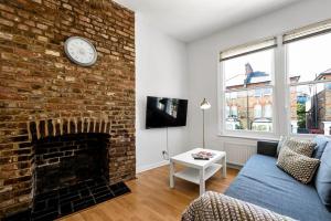 Spacious 1 bed flat close to Crouch End في لندن: غرفة معيشة مع موقد من الطوب وساعة على الحائط