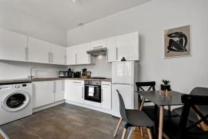 a kitchen with white cabinets and a table with chairs at Spacious 1 bed flat close to Crouch End in London