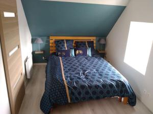 sypialnia z dużym łóżkiem z niebieską kołdrą w obiekcie Gîte Les Pommiers w mieście Montchaton