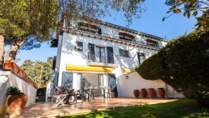 Casa blanca con mesa y sillas en una terraza en GERANIS, en Llafranc