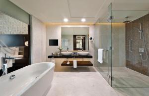 ein Badezimmer mit zwei Waschbecken, einer Badewanne und einem Spiegel in der Unterkunft Marriott Hotel Al Forsan, Abu Dhabi in Abu Dhabi