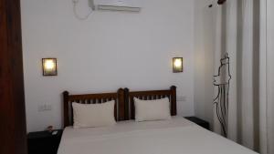 ウェリガマにあるMorning Glory Villaのベッドルーム1室(白い枕2つ付きのベッド1台付)