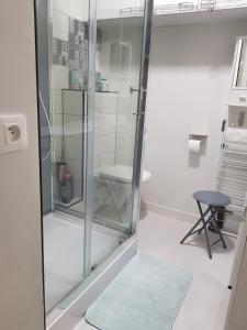 a glass shower in a room with a stool at Port plage a pied 3nuits mini in Le Pouliguen