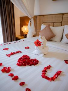 a bed with red rose petals on it at Lasanti Villas Seminyak in Seminyak