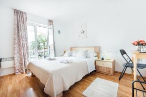 a white bedroom with a bed and a window at Lenić apartman in Fažana