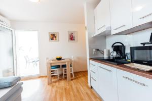 a kitchen with white cabinets and a small table at Lenić apartman in Fažana