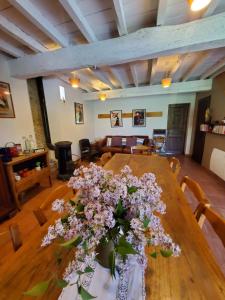 una mesa de madera con un jarrón de flores. en B&B La Ferme de Loubens, en Loubens-Lauragais