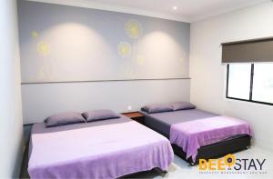 two beds in a room with purple sheets at Melaka Afamosa DAmour Villa 12PAX with Private Pool & BBQ in Kampong Alor Gajah