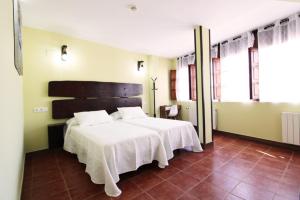 a bedroom with a bed with white sheets and windows at Hotel Rural Frías in Trias