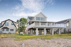 a large house with a balcony on the beach at Cozy Beach - Direct Waterfront! in East Haven