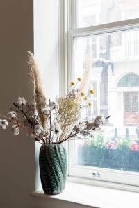 a vase filled with flowers sitting on a window sill at Cosy 1 Bed Apartment in the heart of Mayfair! in London