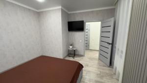 ein Schlafzimmer mit einem Bett und einem TV an der Wand in der Unterkunft ЖК Отау Сити2 in Kökschetau