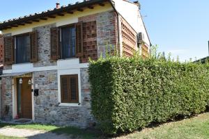 a stone house with a hedge in front of it at appartamento vacanze Sofia house in Capannori