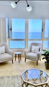 a living room with two chairs and a glass table at ALEX HOMES - Stanley Cozy Apartments with Direct Sea View in Alexandria