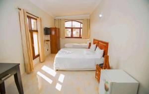 a bedroom with a white bed and a window at Lidia's Place Guest House in Maputo