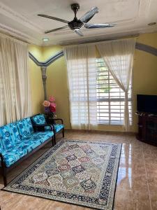 een woonkamer met een blauwe bank en een tapijt bij Teratak Tiga Homestay Padang Besar in Kaki Bukit