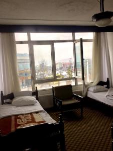 a room with two beds and a chair and a window at KAYAPALI OTEL in Bursa